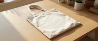 Blank cream canvas tote bag displayed on wooden table with natural lighting, ready for custom design, branding, or printing projects.