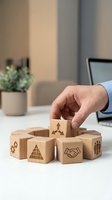 Businessman hand selecting wooden cube with business icons representing strategic planning and corporate decision making in modern office environment.