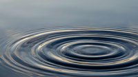 Concentric water ripples spreading outward in calm blue surface creating peaceful meditation and tranquility concept for wellness and mindfulness applications.