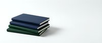 Stack of navy blue and green hardcover notebooks on white background, minimalist stationery for office, school, and creative planning.