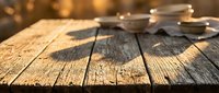 Rustic weathered wooden table surface with warm bokeh lights in background creating cozy atmosphere for product display and food photography presentations.