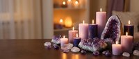 Relaxing spa setup with purple amethyst crystals and lavender candles creating peaceful meditation atmosphere for wellness and spiritual healing rituals.