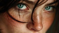 Young woman with freckles and blue eyes wearing round glasses looking directly at camera with natural lighting highlighting facial features and skin texture.