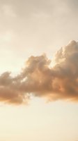 Dramatic golden sunset clouds in warm beige sky creating peaceful atmospheric mood for meditation and wellness backgrounds.