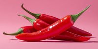Fresh red chili peppers arranged on pink background, spicy hot peppers for cooking and culinary use in kitchen recipes and food preparation.