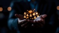 Hands holding glowing network of people icons representing social connections, teamwork and community building in dark atmospheric setting.