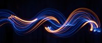 Abstract flowing light trails in blue and orange neon colors swirling across dark background, suitable for modern design, technology, and creative projects.