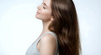 Young Caucasian woman with long brown hair in profile showing healthy shiny hair care and beauty routine on white background for wellness advertising.