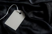 Blank price tag on luxurious black leather fabric with soft folds and texture, ready for branding or product information.