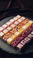 Assorted Turkish delight lokum confections with nuts and dried fruits arranged on dark slate board for gourmet dessert presentation and culinary photography.