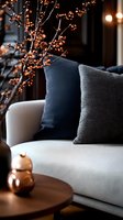 Cozy autumn home interior with white sofa, dark cushions, copper decorative branches and warm lighting creating intimate atmosphere for seasonal decor.
