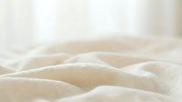 Soft, folded cream-colored fabric with gentle waves and natural texture, suitable for textile, fashion, and home decor design projects.