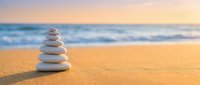 Zen stone stack on sandy beach at sunset with ocean waves creating peaceful meditation and balance concept for wellness and mindfulness practices.