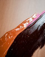 Abstract artistic composition featuring bold diagonal brushstrokes in brown, black and pink tones against neutral background, creating dynamic movement and texture.