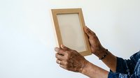 Hands holding empty wooden frame against white background, suitable for mockups, presentations, and design projects.