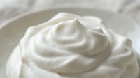 Creamy white swirled texture in bowl, smooth dairy product or cosmetic cream with rich consistency for skincare, food photography and wellness concepts.