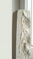 Ancient weathered stone column with intricate carved relief patterns and textured surface in minimalist interior setting for architectural design projects.