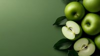 Fresh green apples and sliced halves with dark leaves arranged on green background with copy space. Minimalist food photography for healthy lifestyle concept.