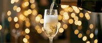 Champagne being poured into a glass with golden bokeh lights in the background, perfect for celebration, festive events, and luxury beverage concepts.