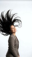 Happy Asian businesswoman with flowing hair in motion wearing professional gray suit against white background for corporate marketing materials.