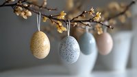 Decorative Easter eggs in pastel colors hanging on spring flowering branch with delicate blossoms. Speckled pattern adds natural texture to seasonal display.