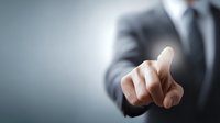 Businessman in formal suit pointing finger at virtual screen, representing digital technology interaction and corporate decision making.