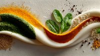 Fresh herbs and colorful spices arranged in creative wave pattern with basil leaves, turmeric, paprika and dried seasonings on white background for culinary design.