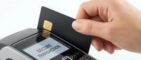 Caucasian hand inserting black credit card into payment terminal for secure transaction processing and contactless checkout.