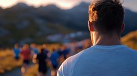 Rear view of male runner in white t-shirt at sunset marathon event with blurred participants in background against mountain landscape. Golden hour athletic scene.