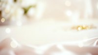 Soft dreamy bokeh background with warm golden lights and delicate fabric textures creating romantic atmosphere for wedding or luxury product displays.