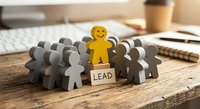 Leadership concept with yellow figure standing out from crowd on wooden desk in modern office environment for business motivation and team management.