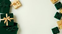 Wrapped gift boxes in emerald green and gold with satin bows arranged on cream background, isolated flat lay composition for holiday marketing, greeting cards, and seasonal promotional designs.