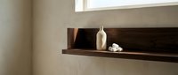 Wooden wall shelf displaying white ceramic vase and decorative stones in minimalist interior design setting for home decor projects.