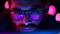 Close up portrait of bearded man in glasses illuminated by vibrant neon pink and blue lights creating dramatic cyberpunk atmosphere with bokeh effect in background.