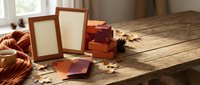 Autumn memories collection with empty photo frames, gift boxes and fall leaves on rustic wooden table in warm sunlight for seasonal crafting projects.