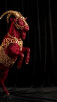 Ornate red demon creature with golden horns and decorative patterns rearing up against dark theatrical backdrop for fantasy and horror themed projects.