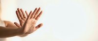 Open hands reaching upward in prayer or meditation gesture against soft light background for spiritual wellness concepts.