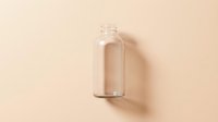 Empty glass bottle with clear cylindrical shape on neutral beige background, suitable for cosmetics, skincare, essential oils, perfume, and beverage packaging design mockups.