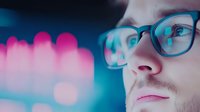 Young caucasian man in glasses illuminated by vibrant neon lights creating modern urban nightlife atmosphere with bokeh effects in background.