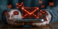 Glowing red email icons floating above smartphone held in hands against dark background, depicting digital communication and message notification concept.