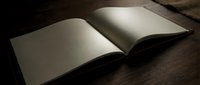 Open blank book with empty white pages on wooden surface in dramatic lighting for writing, reading, education and literary concepts.
