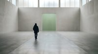 Silhouette of person walking toward glowing green door in empty concrete corridor, symbolizing opportunity, choice, and new beginnings for business and motivation concepts.