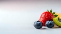 Fresh mixed berries and kiwi fruit arranged on clean white background with copy space for healthy eating and nutrition concepts.