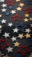 Colorful star shapes scattered on dark surface featuring red white blue gold stars in various sizes and styles for patriotic holiday decorations and craft projects.