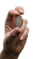 Male hand holding vintage silver dollar coin between fingers on white background isolated for numismatic collecting and investment concepts.