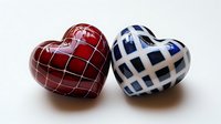 Red and blue ceramic hearts with geometric pattern on white background, decorative romantic elements for valentines day and love concepts.