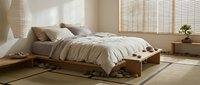 Minimalist bedroom with low wooden platform bed, neutral bedding, natural light from shoji screens, and zen aesthetic for interior design and home decor projects.