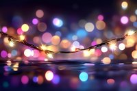 String lights reflecting on water surface against blurred colorful bokeh background creating magical festive atmosphere with warm and cool light spots.