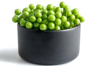 Fresh green peas in modern black ceramic bowl on white background, minimalist food styling for healthy eating and cooking concepts.