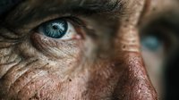 Close-up portrait of elderly person with striking blue eyes and deeply wrinkled weathered skin showing age and life experience in detailed macro photography.